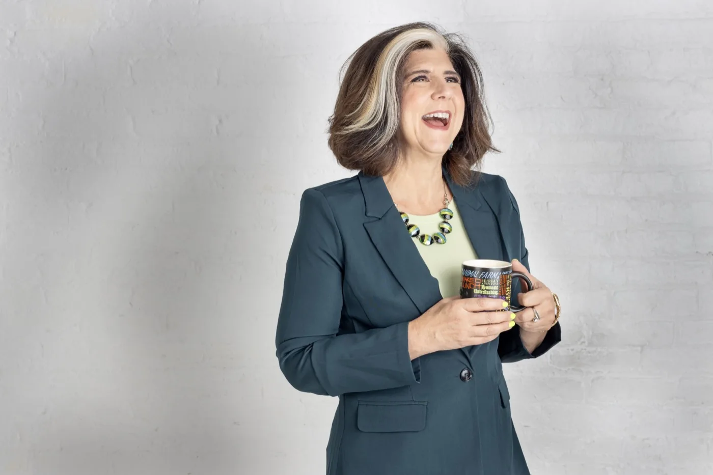 Robin Colucci laughing in a teal blazer, holding a mug
