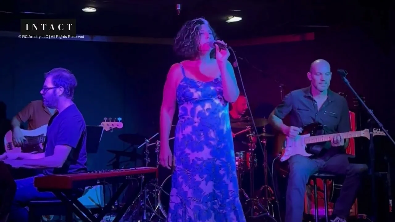 Robin Colucci in a blue floral dress singing with her live band at the Wine Country Showcase in Solvang